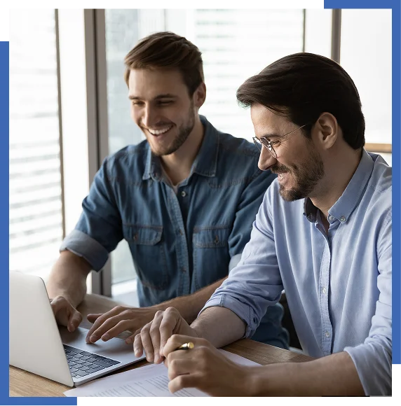 Two men smiling at laptop